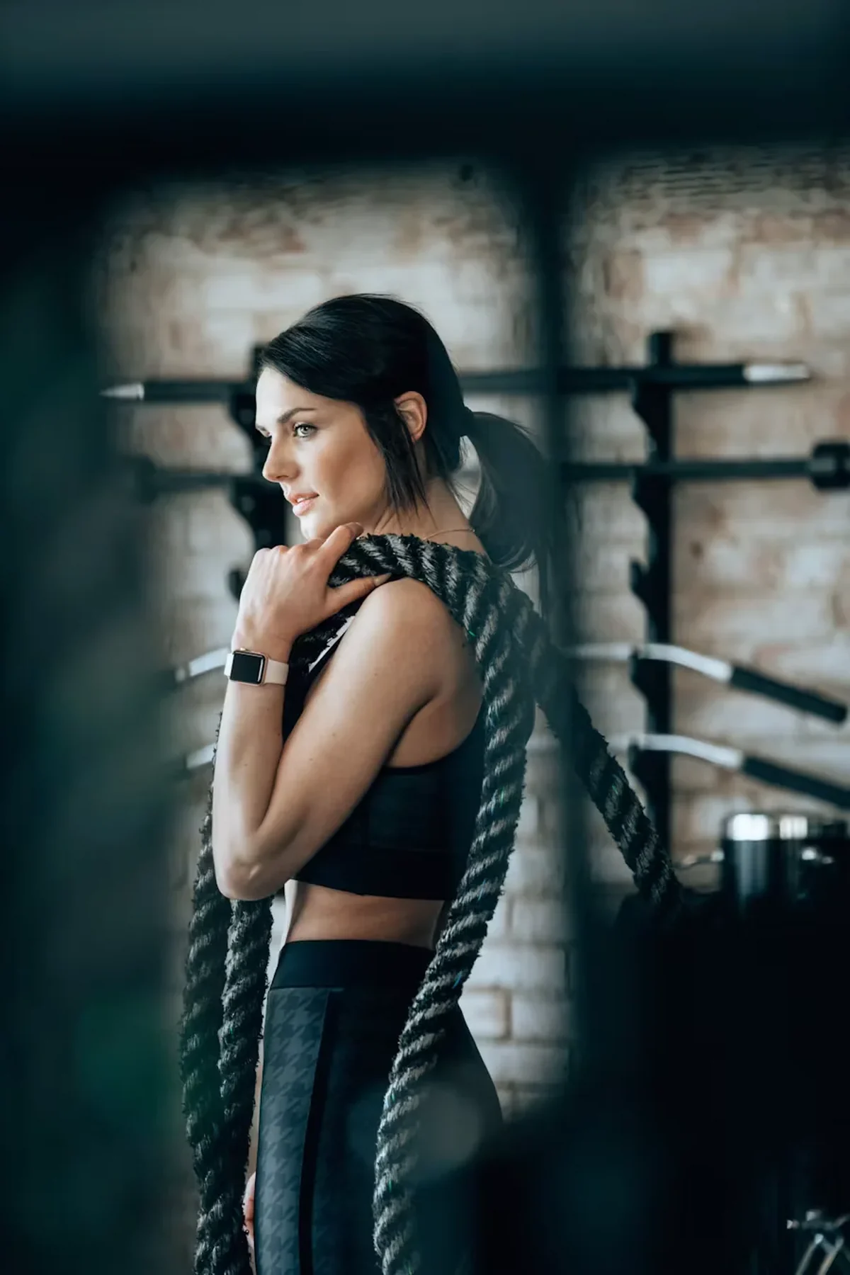 Woman with a training rope over her shoulder in a gym
